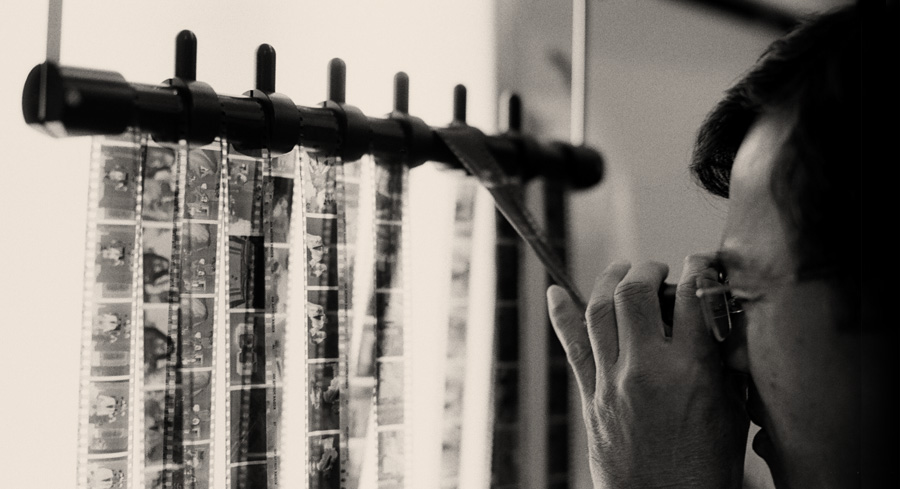 film-lab-technician-examining-film-negatives